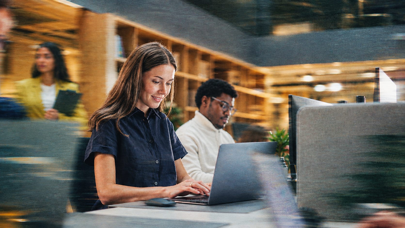 People working at laptops in a busy office